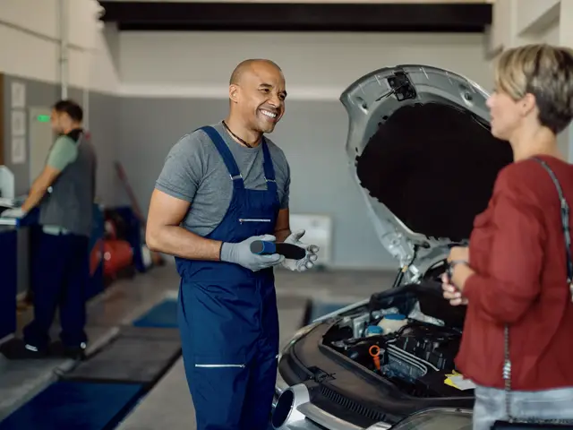 Mecánico sonriendo mientras le explica el motor a una clienta